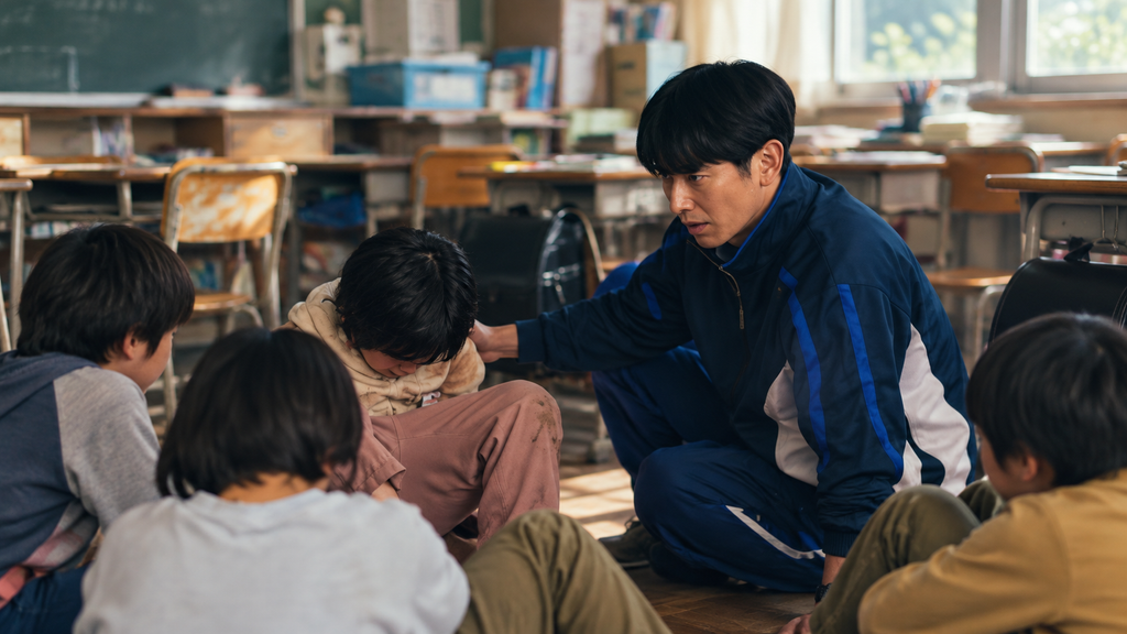 映画『怪物』の保利先生をイメージした男性教師が、教室で児童に向き合い、周囲の子どもたちが見守るイラスト